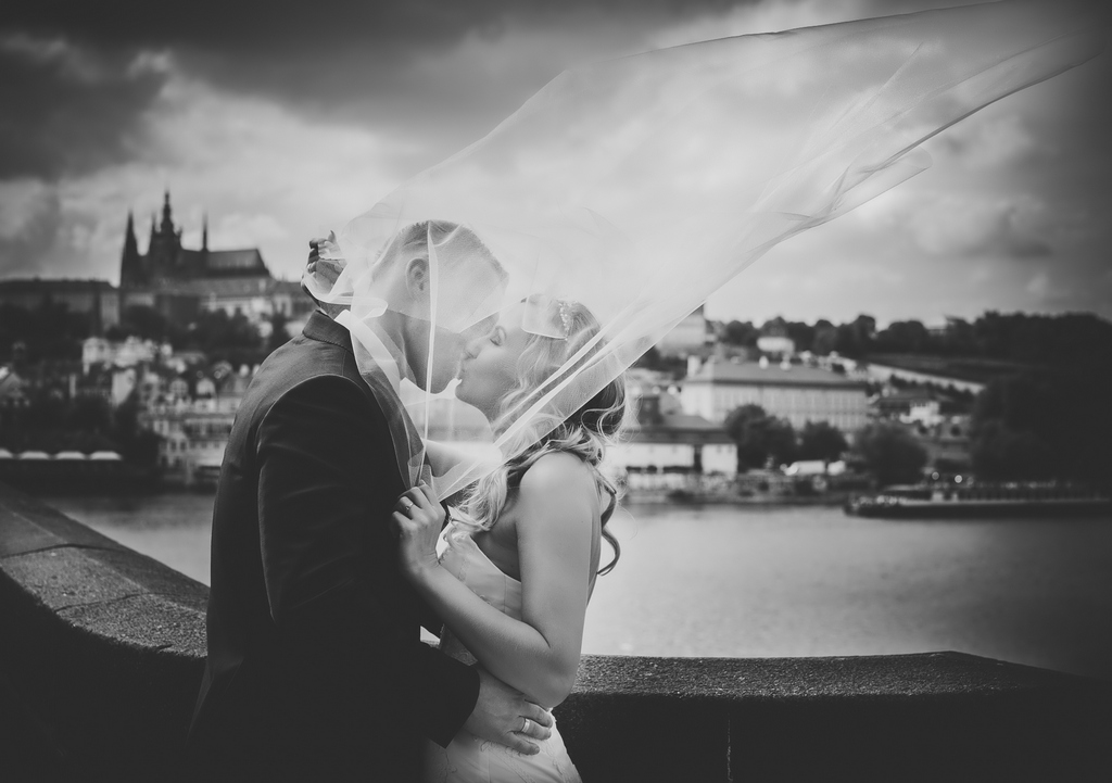 Para Młoda całuje się pod welonem na moście karola w Pradze
