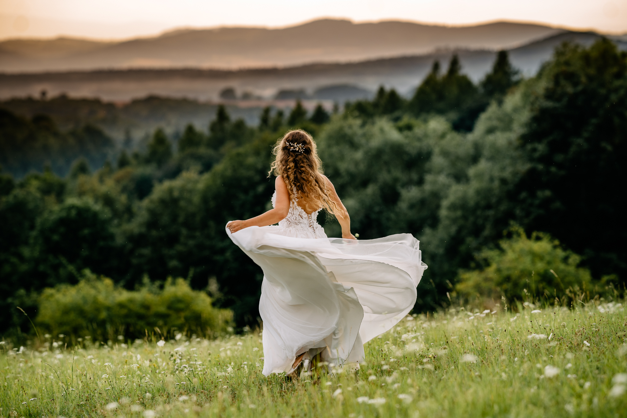 kobieta w białej sukni tańczy na tle górskiego krajobrazu